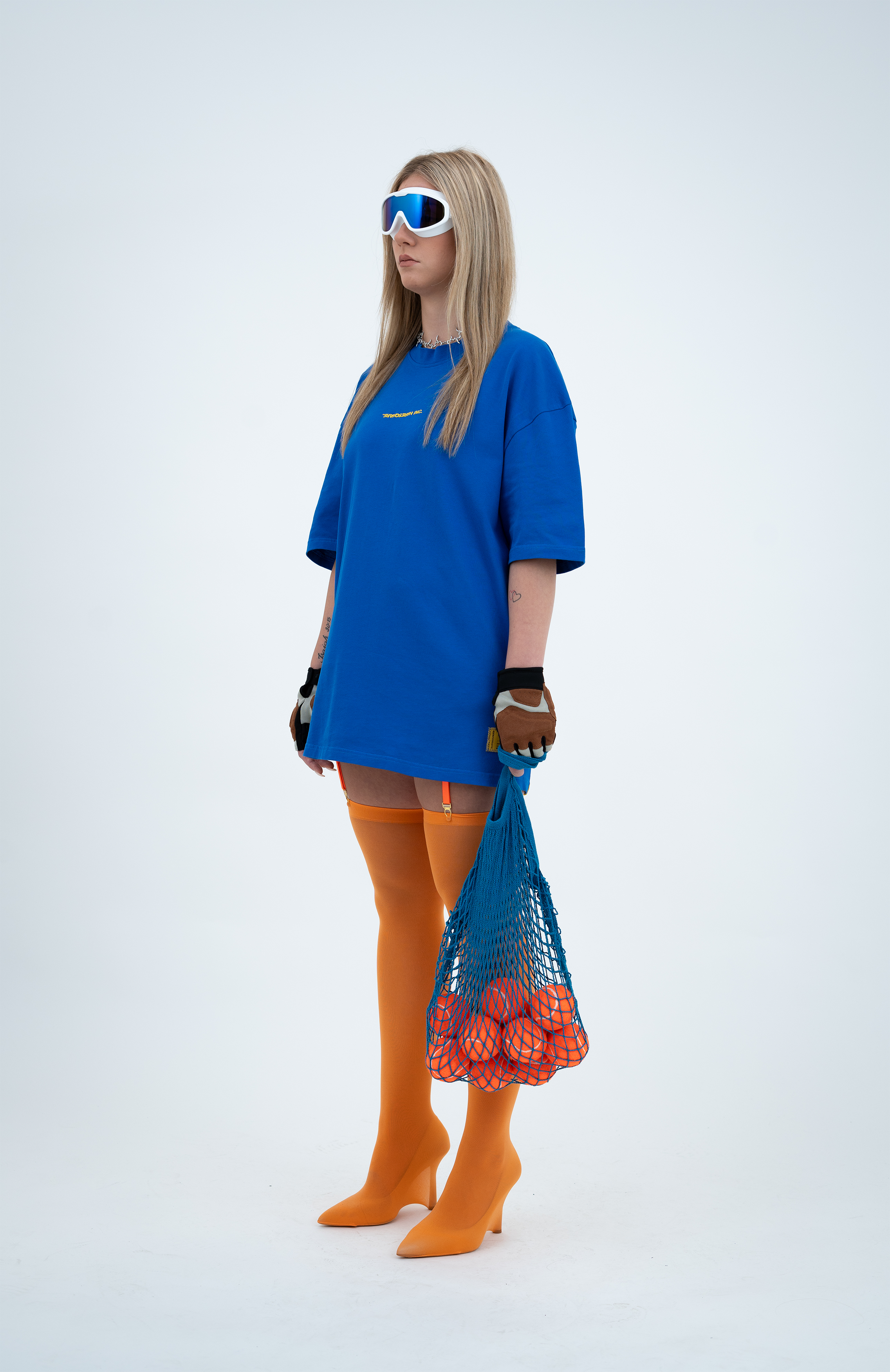 Model in the Haresquare Nautical Blue T-shirt with a Yellow print, styled with Haresquare mini skirt, designer sunglasses, and designer boots in orange – unisex luxury sportswear from Ireland.
