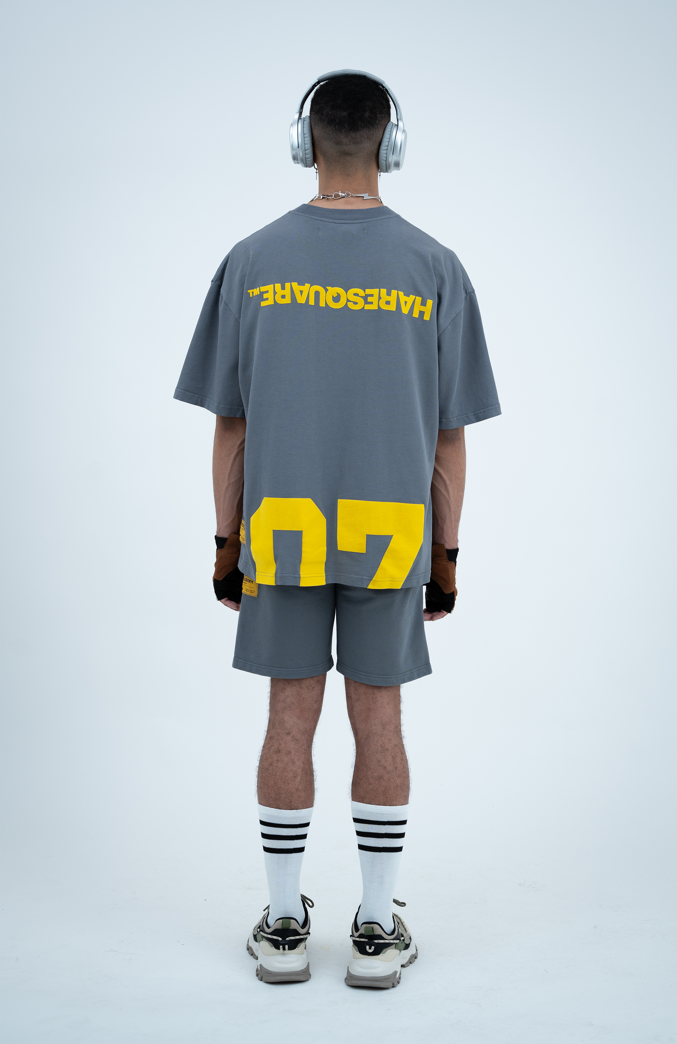 Model in the Haresquare Steey Grey T-shirt with a Yellow print, styled with Haresquare Grey shorts and designer sunglasses – unisex luxury sportswear from Ireland.