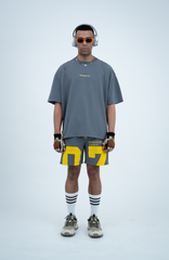 Model in the Haresquare Steey Grey T-shirt with a Yellow print, styled with Haresquare Grey shorts and designer sunglasses – unisex luxury sportswear from Ireland.