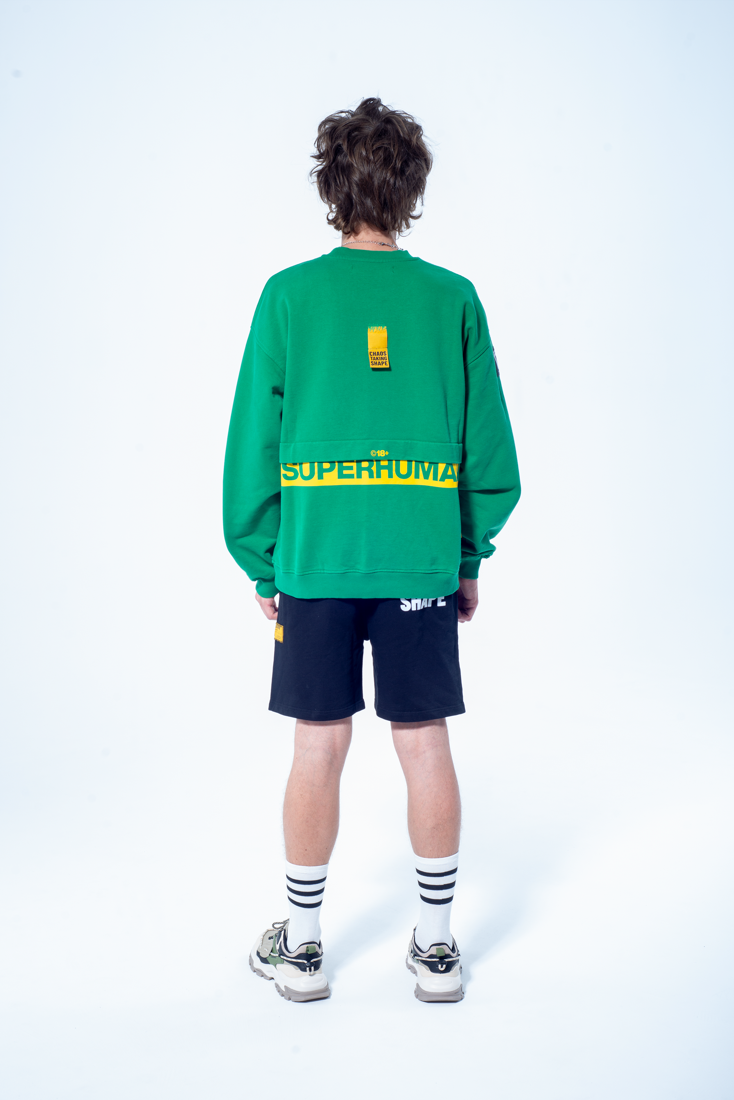 Model in the Haresquare Superhuman Abundant Green sweatshirt with Yellow print, styled with Haresquare black shorts – unisex luxury streetwear from Ireland.