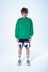 Model in the Haresquare Superhuman Abundant Green sweatshirt with Yellow print, styled with Haresquare black shorts – unisex luxury streetwear from Ireland.