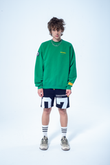 Model in the Haresquare Superhuman Abundant Green sweatshirt with Yellow print, styled with Haresquare black shorts – unisex luxury streetwear from Ireland.