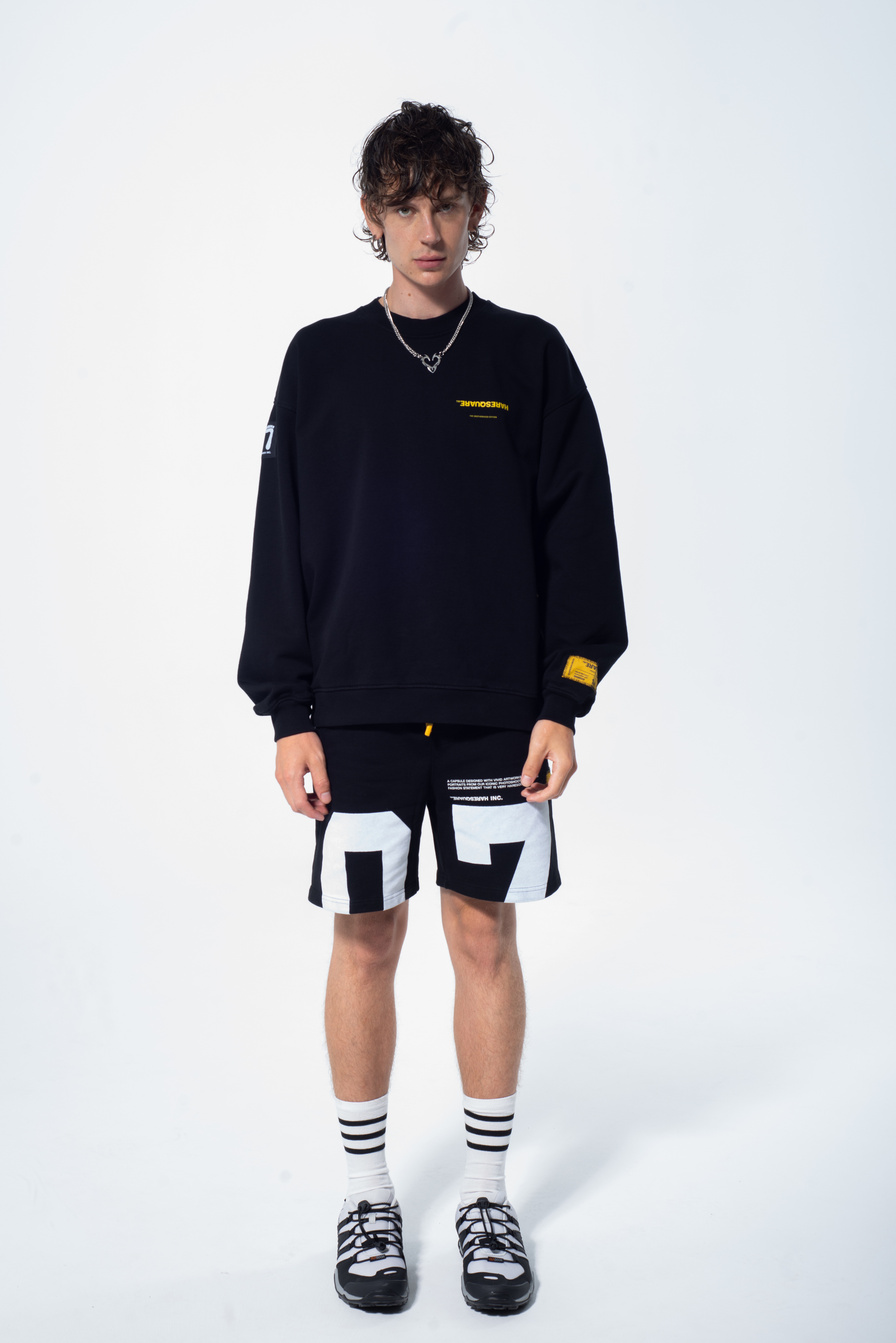 Model in the Haresquare Superhuman black sweatshirt with yellow print, styled with Haresquare black shorts – unisex luxury streetwear from Ireland.