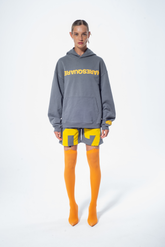 Model in the Haresquare Steel Grey Hoodie with a Yellow print, styled with Haresquare Grey shorts and orange designer boots – unisex luxury streetwear from Ireland