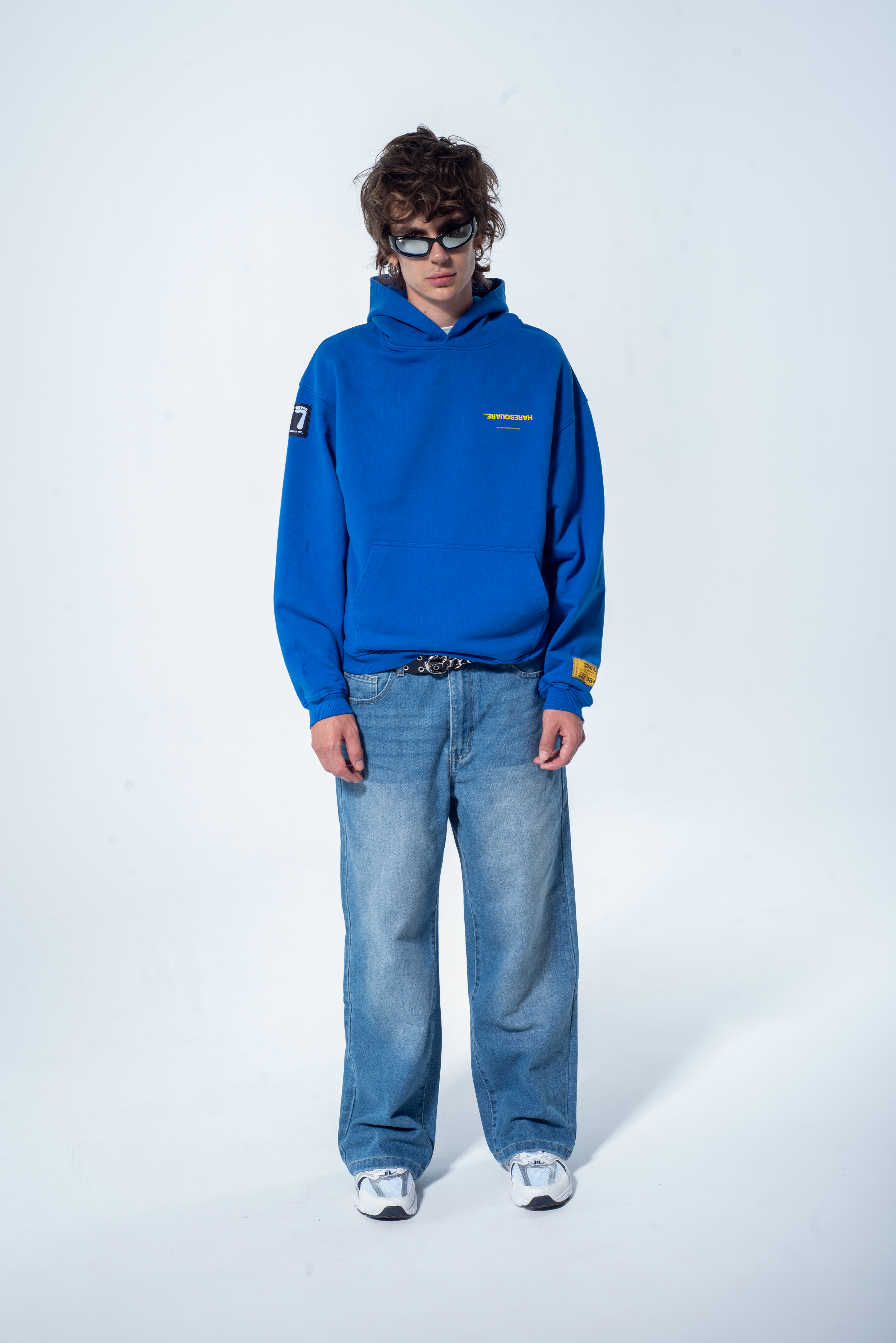 Model in the Haresquare Superhuman Nautical blue hoodie with yellow print, styled with Haresquare denim jeans – unisex luxury streetwear from Ireland.