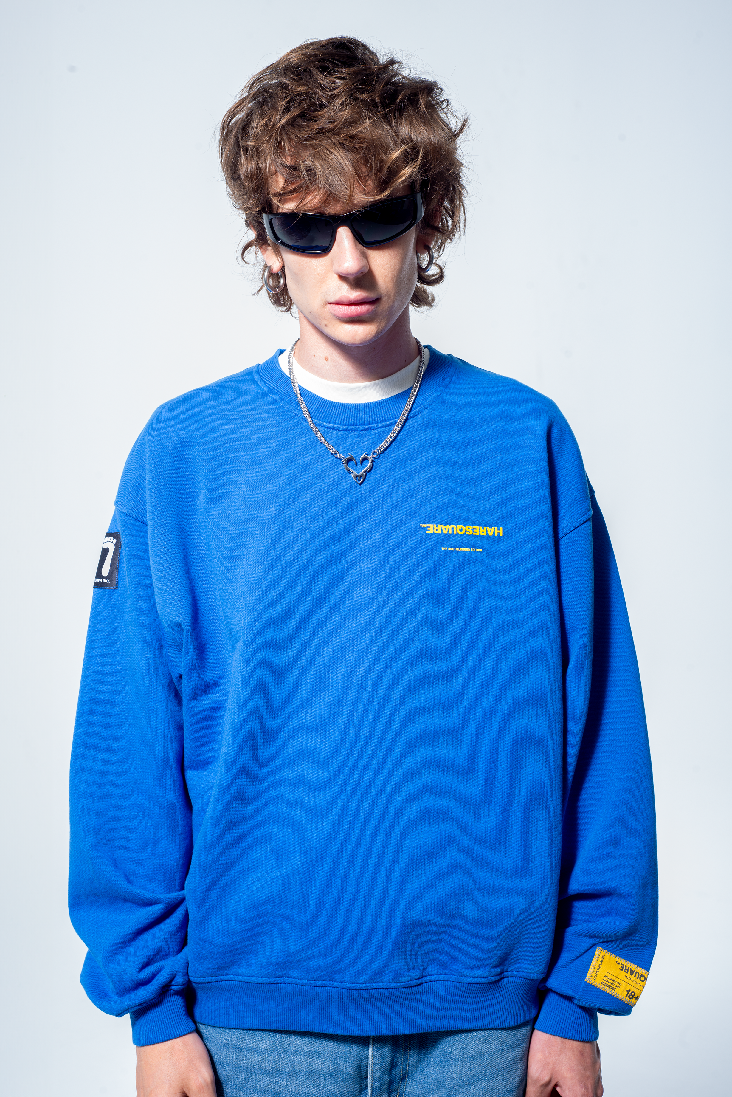 Model in the Haresquare Superhuman Nautical Blue sweatshirt with Yellow print, styled with Haresquare Blue denim jeans and haresquare bag – unisex luxury streetwear from Ireland.