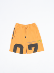 Close-up of Haresquare orange shorts with a grey print – unisex luxury streetwear from Ireland.