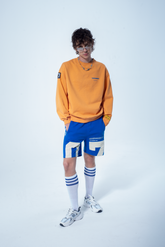 Model in the Haresquare Superhuman Apricot Tan sweatshirt with Blue print, styled with Haresquare Blue shorts – unisex luxury streetwear from Ireland.