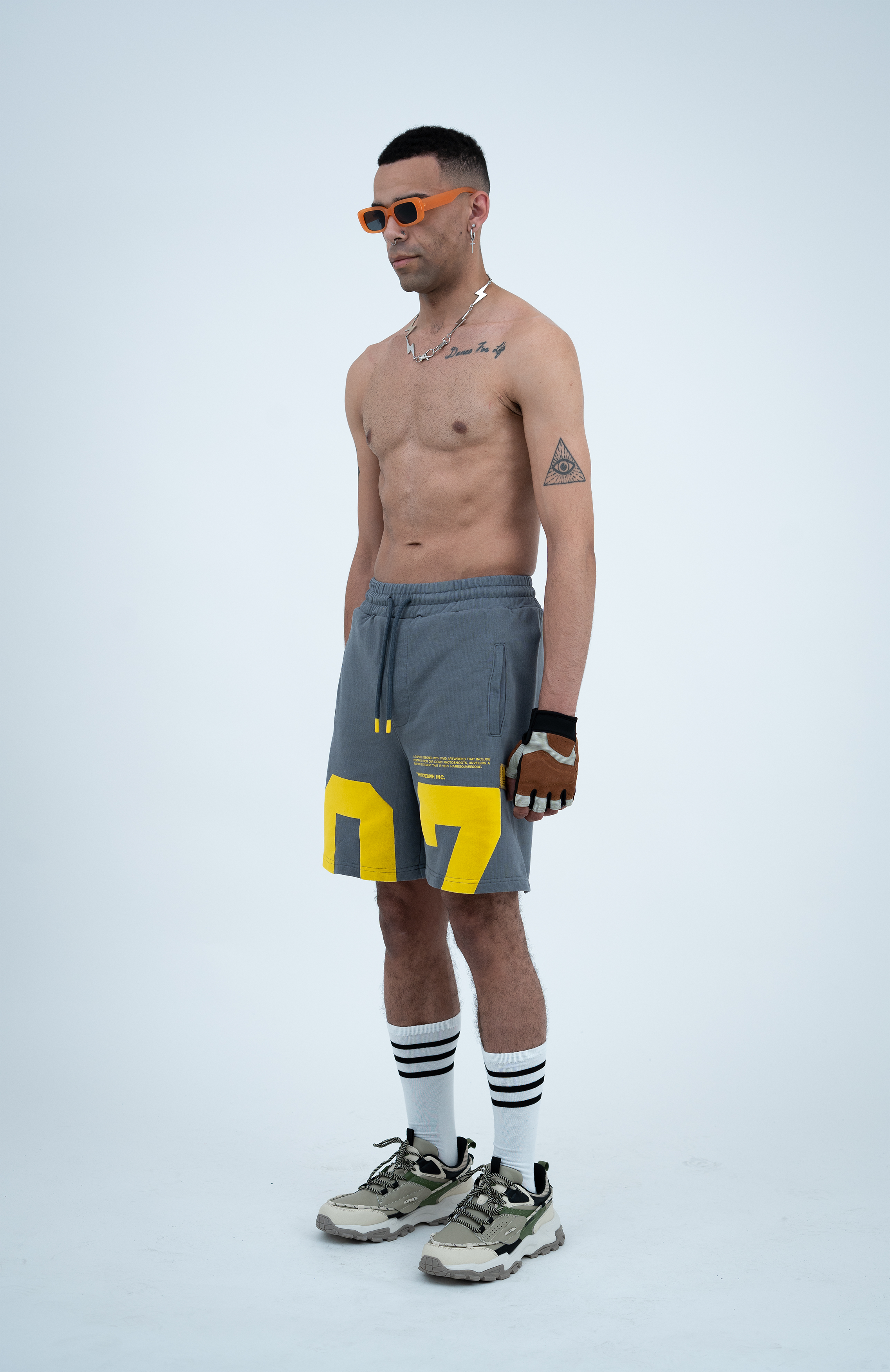 Model in the Haresquare steel grey shorts with a yellow print, styled with Haresquare luxury sunglasses – unisex luxury streetwear from Ireland.