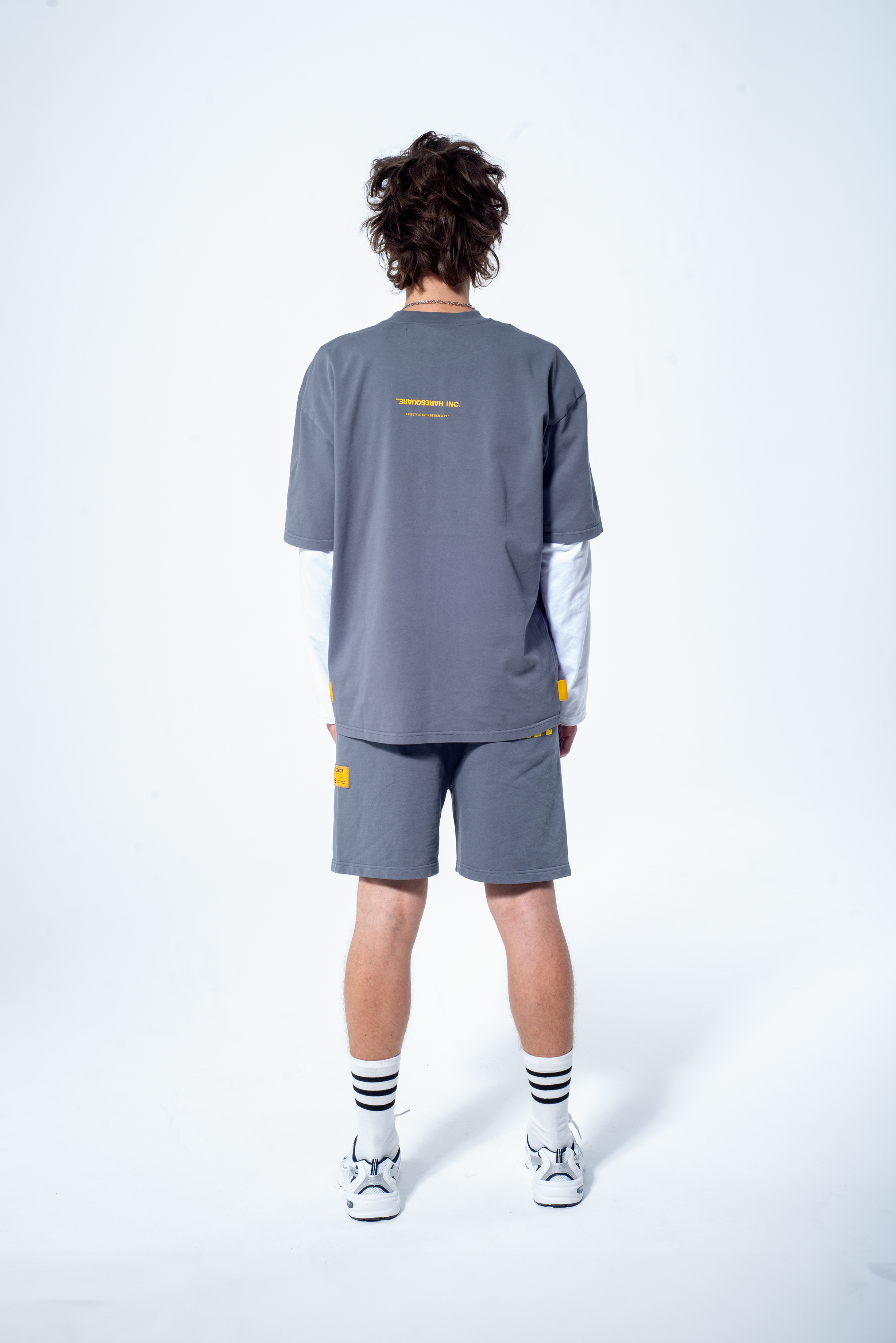 Model in the Haresquare steel grey tshirt with a yellow print, styled with Haresquare shorts in grey – unisex luxury streetwear from Ireland.