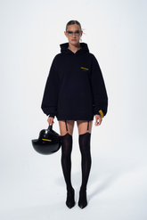 Model in the Haresquare Superhuman black hoodie with yellow print, styled with black helmet – unisex luxury streetwear from Ireland.