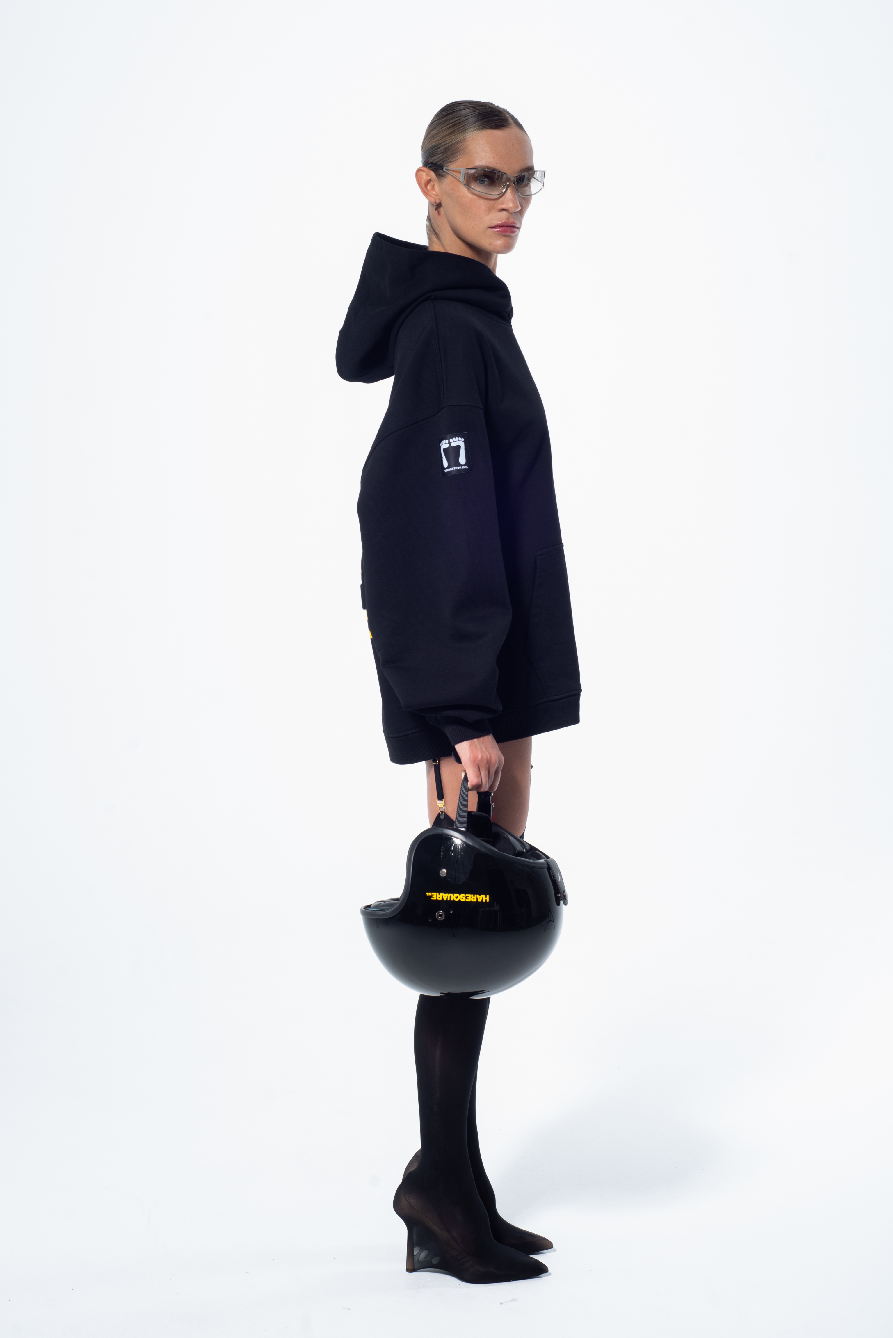 Model in the Haresquare Superhuman black hoodie with yellow print, styled with black helmet – unisex luxury streetwear from Ireland.