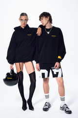 Model in the Haresquare Superhuman black hoodie with yellow print, styled with black helmet – unisex luxury streetwear from Ireland.