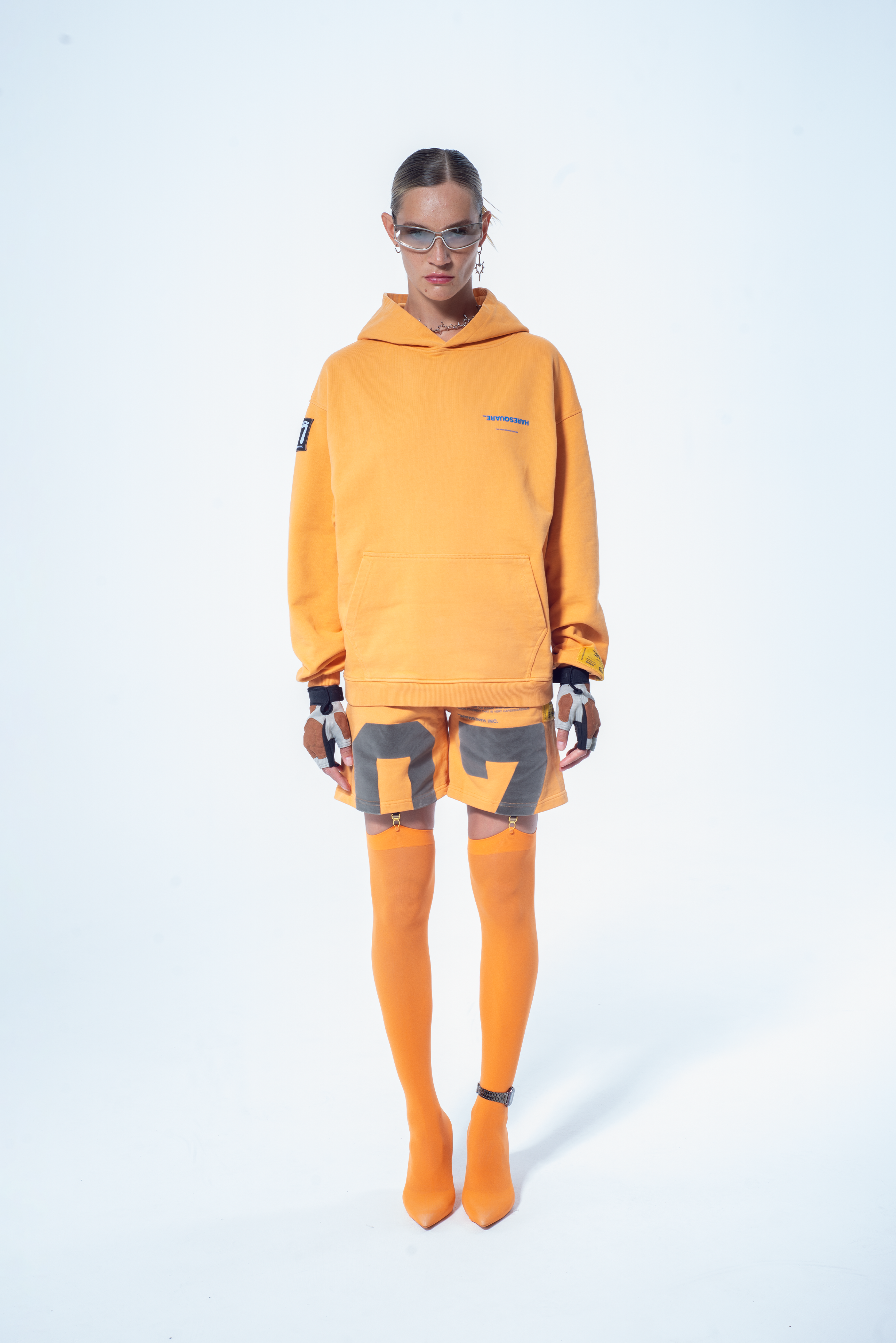 Model in the Haresquare Superhuman Apricot tan hoodie with Blue print, styled with Haresquare shorts – unisex luxury streetwear from Ireland.