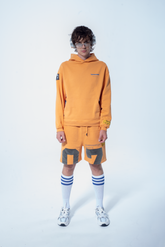 Model in the Haresquare Superhuman Apricot tan hoodie with Blue print, styled with Haresquare shorts – unisex luxury streetwear from Ireland.