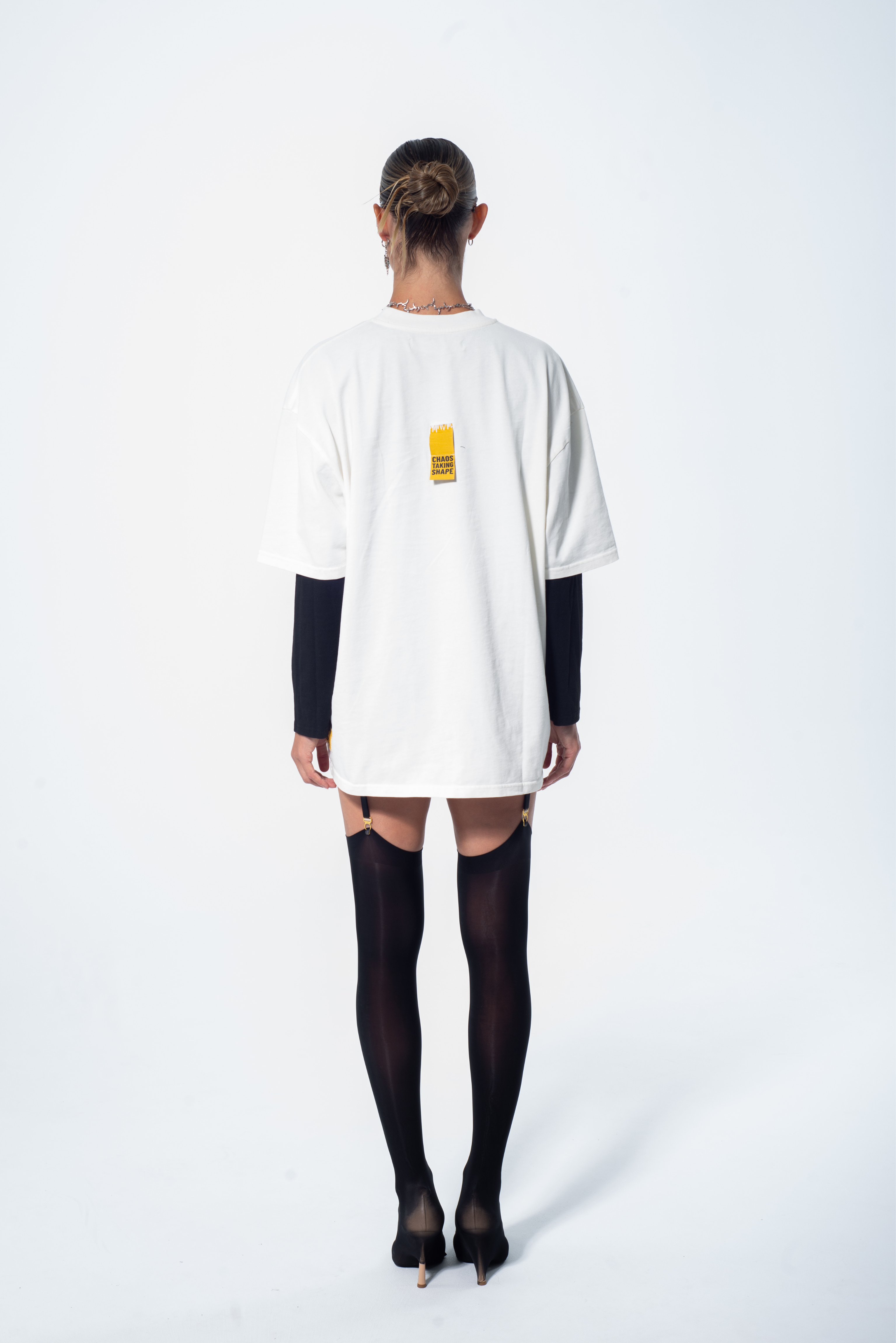 Model in the Haresquare vintage white tshirt with a bold graphic print, styled with Haresquare mini skirt and black designer boots – unisex luxury streetwear from Ireland.