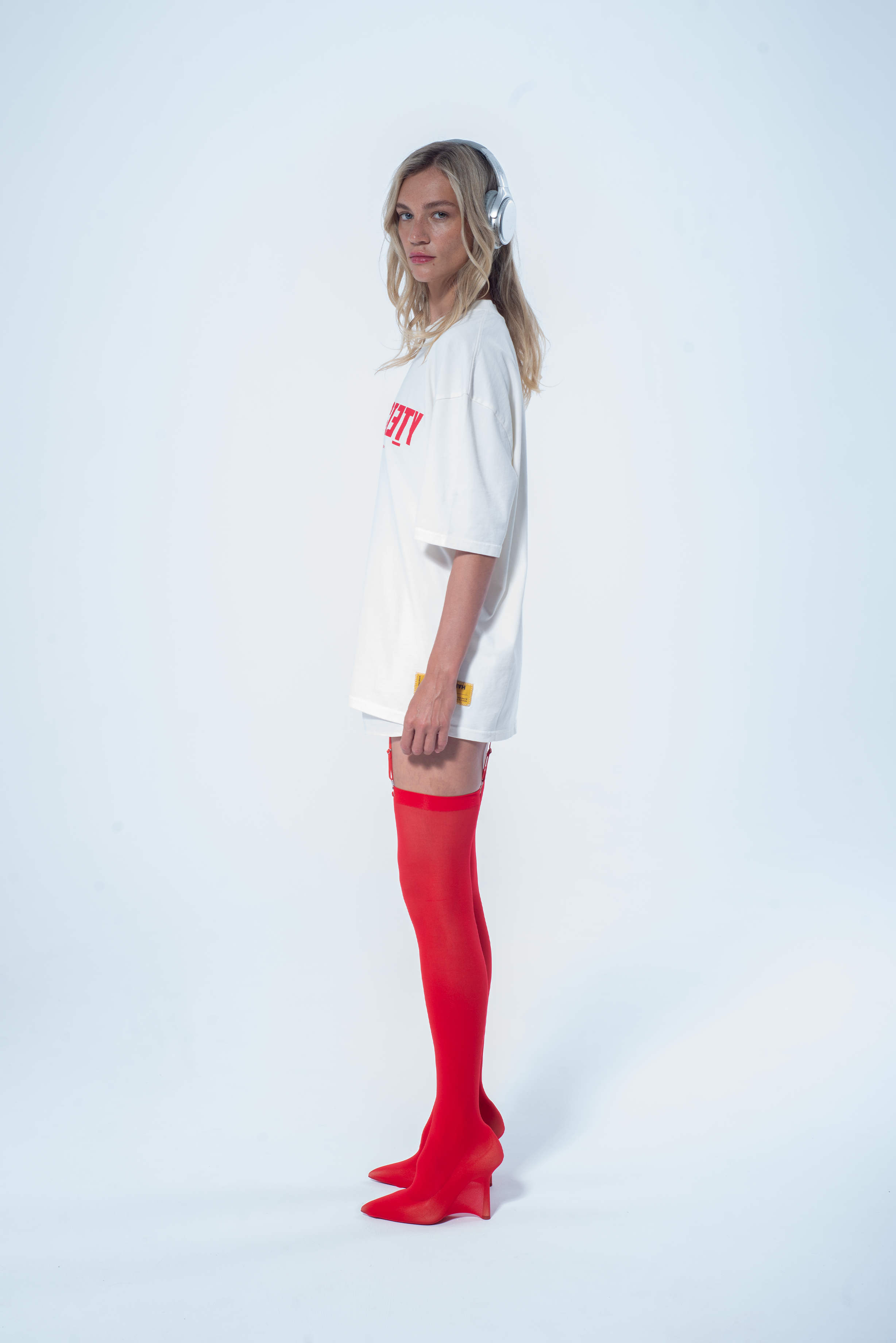 Model in the Haresquare vintage white tshirt with F*CK SOCIETY graphic print in red, styled with Haresquare mini skirt and designer boots – unisex luxury streetwear from Ireland.