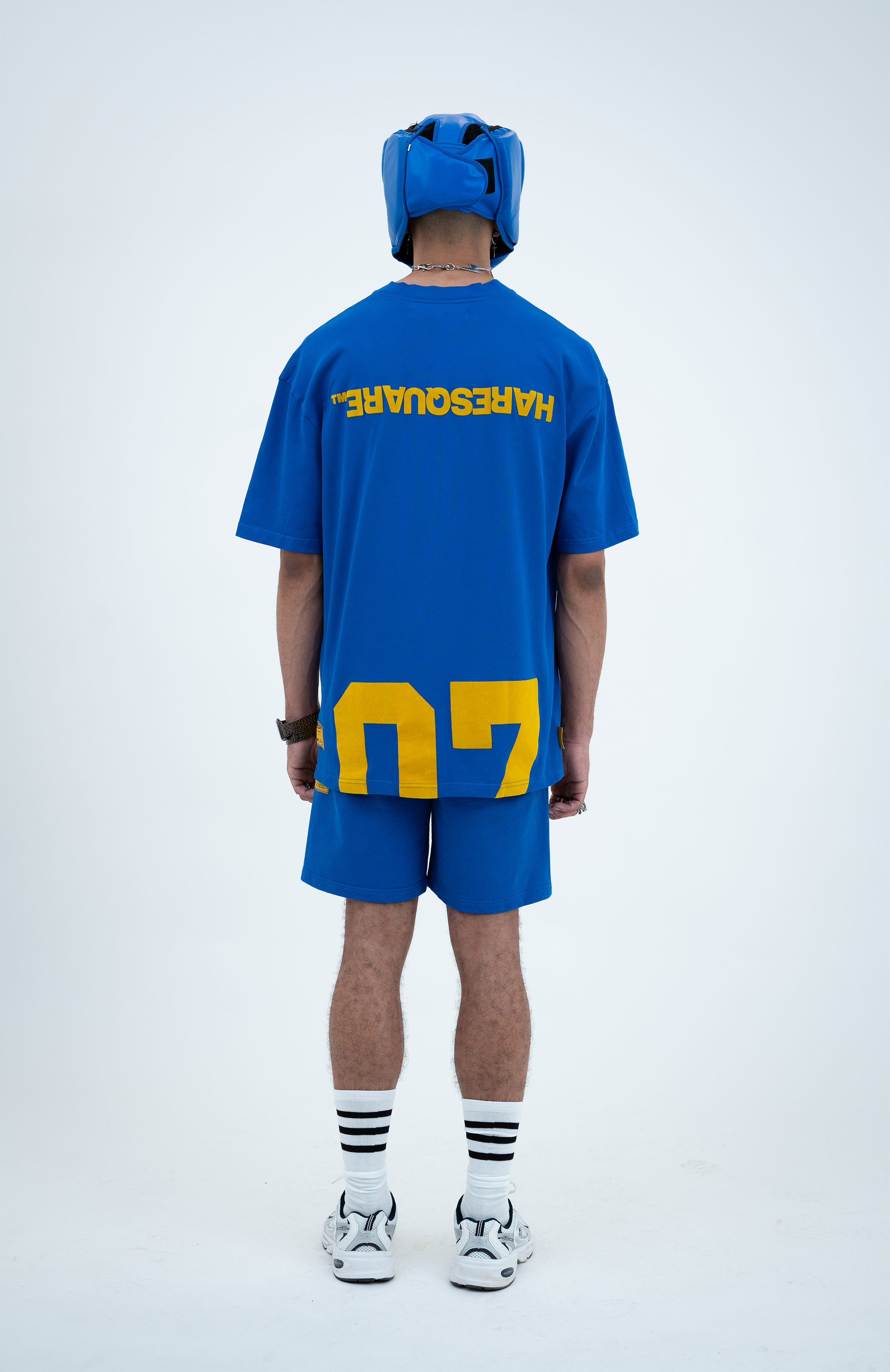 Model in the Haresquare Nautical Blue T-shirt with a Yellow print, styled with Haresquare blue shorts and sports accessory – unisex luxury sportswear from Ireland.