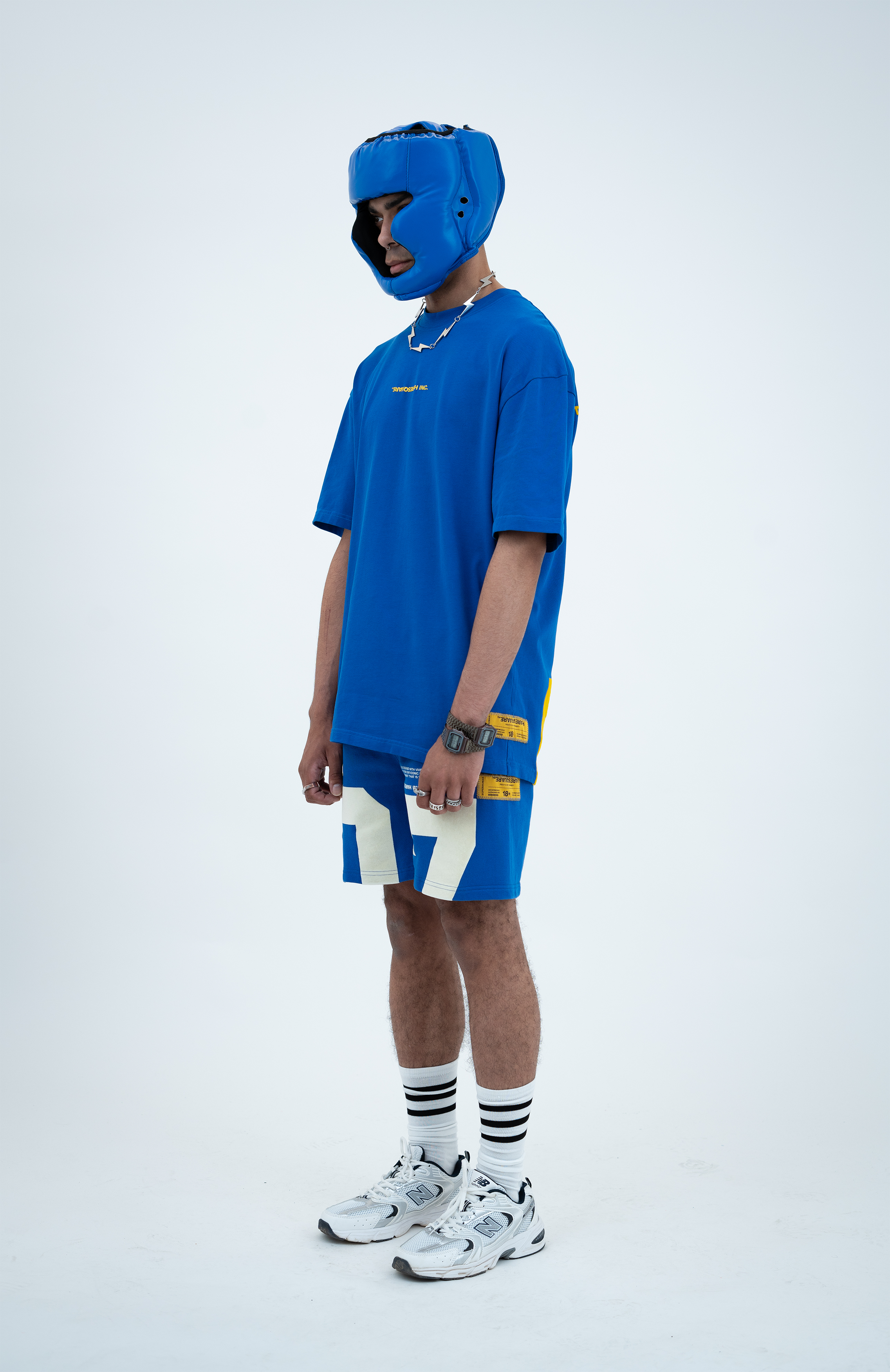 Model in the Haresquare Nautical Blue T-shirt with a Yellow print, styled with Haresquare blue shorts and sports accessory – unisex luxury sportswear from Ireland.