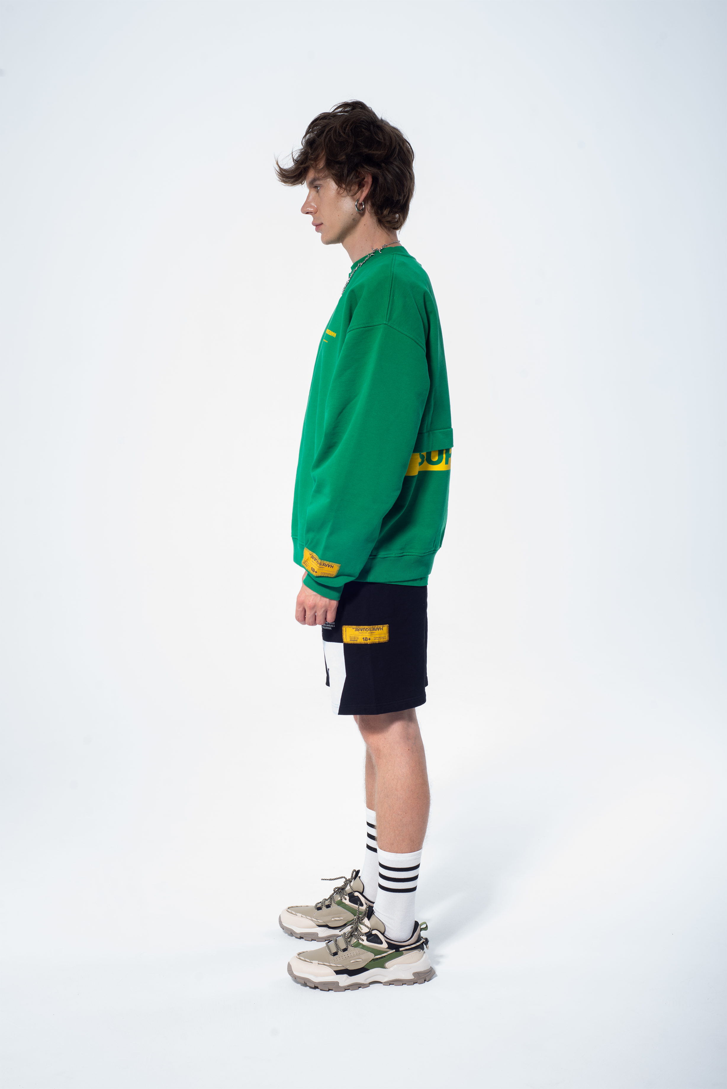 Model in the Haresquare Superhuman Abundant Green sweatshirt with Yellow print, styled with Haresquare black shorts – unisex luxury streetwear from Ireland.