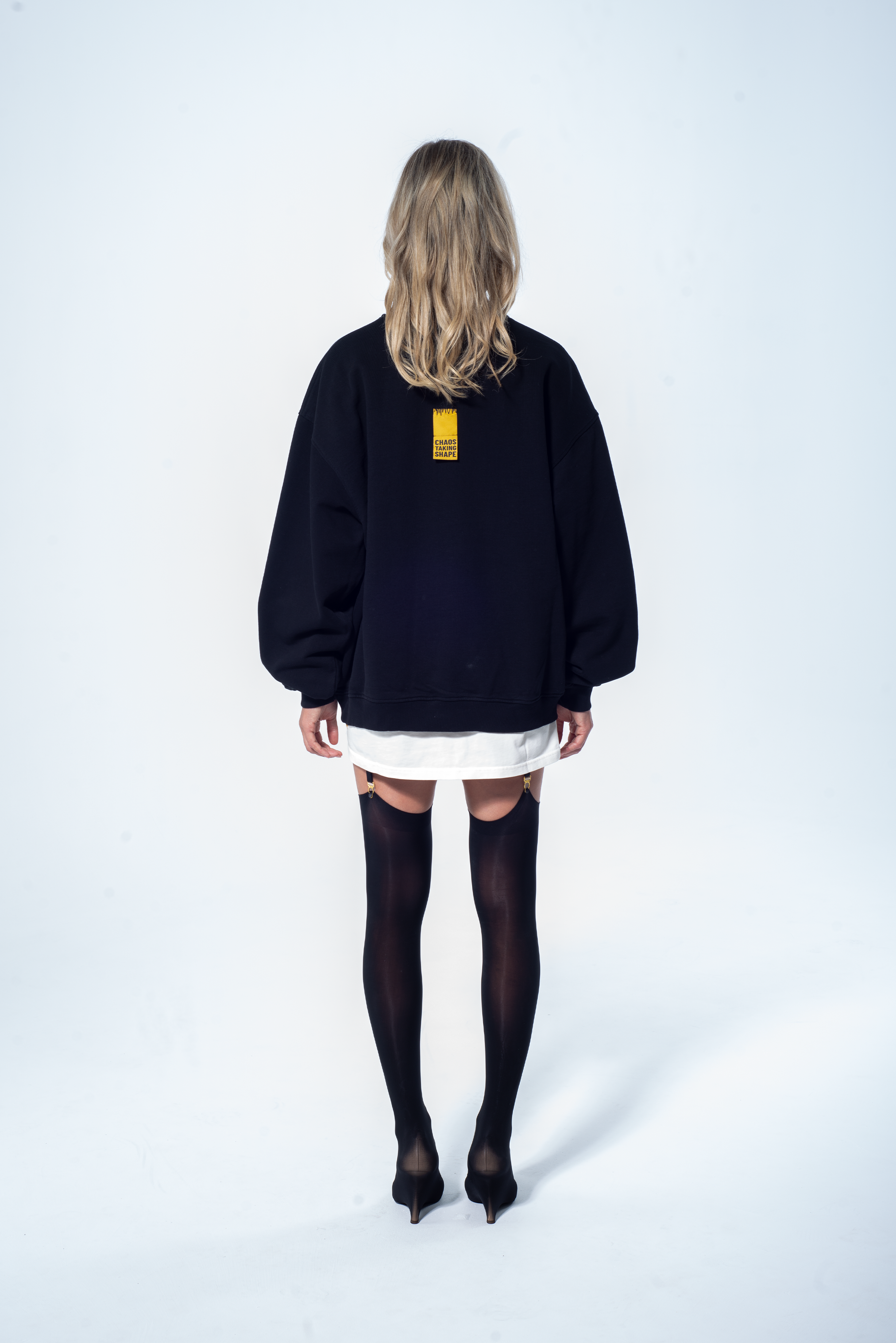 Model in the Haresquare Black sweatshirt with graphic print, styled with Haresquare white skirt – unisex luxury streetwear from Ireland.