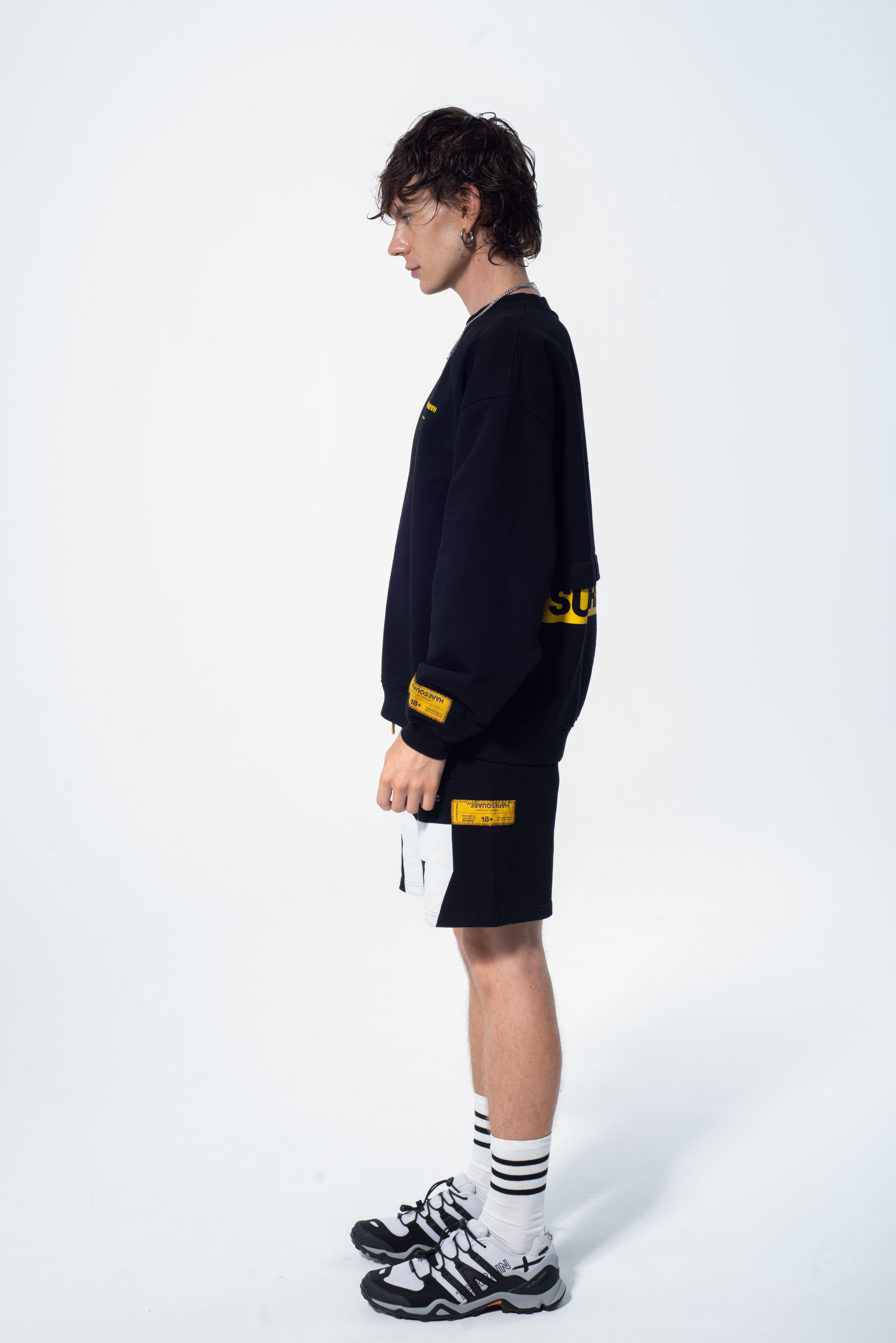 Model in the Haresquare Superhuman black sweatshirt with yellow print, styled with Haresquare black shorts – unisex luxury streetwear from Ireland.