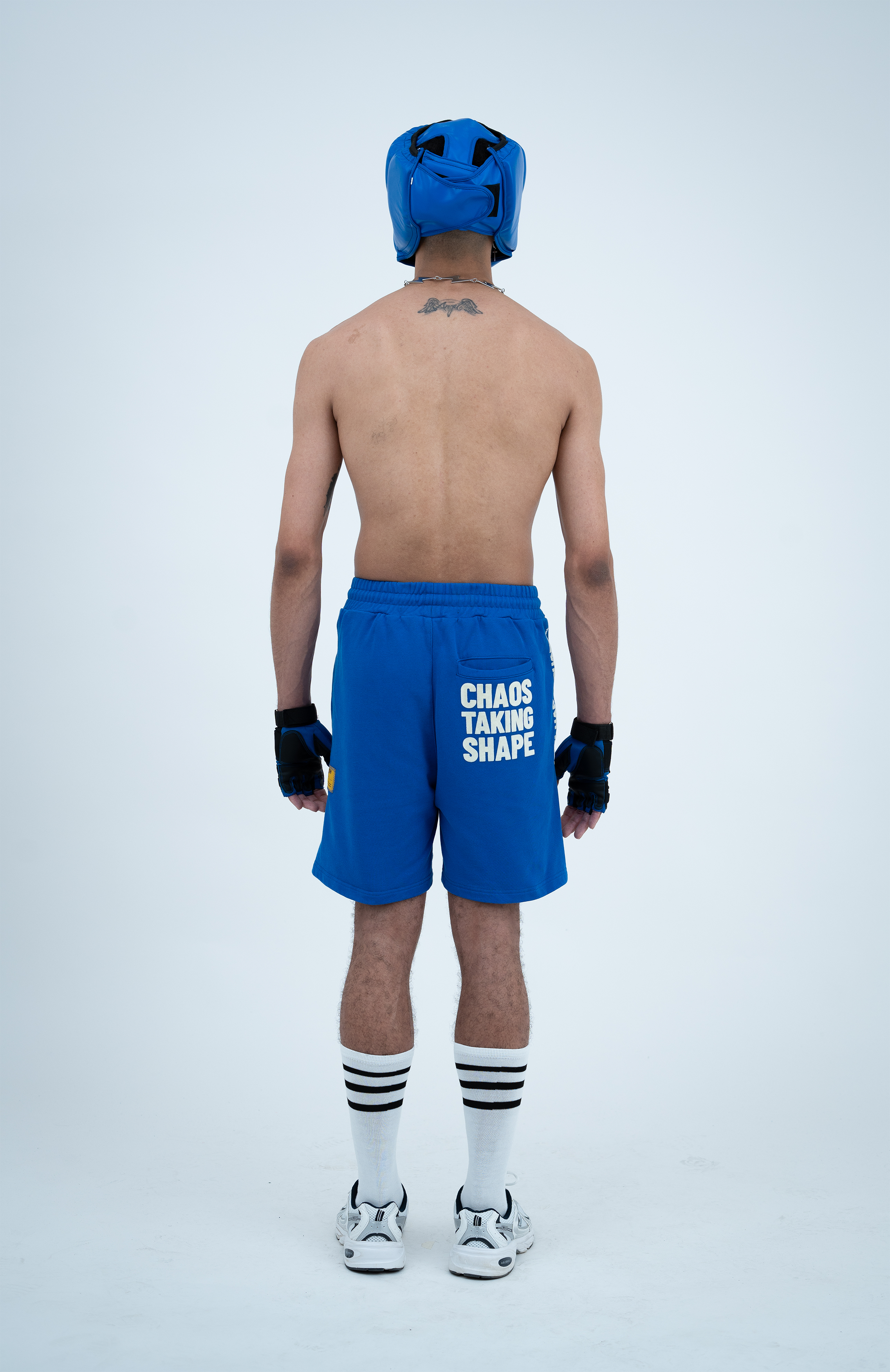 Model in the Haresquare Nautical Blue shorts with a White print, styled with sports accessory – unisex luxury streetwear from Ireland.