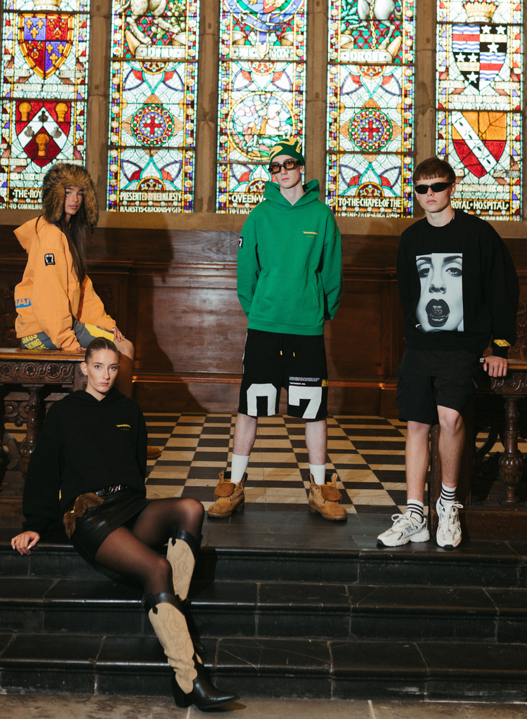 Haresquare unisex luxury streetwear collection featuring hoodies and shorts, photographed in a historic Irish hall with stained glass windows.