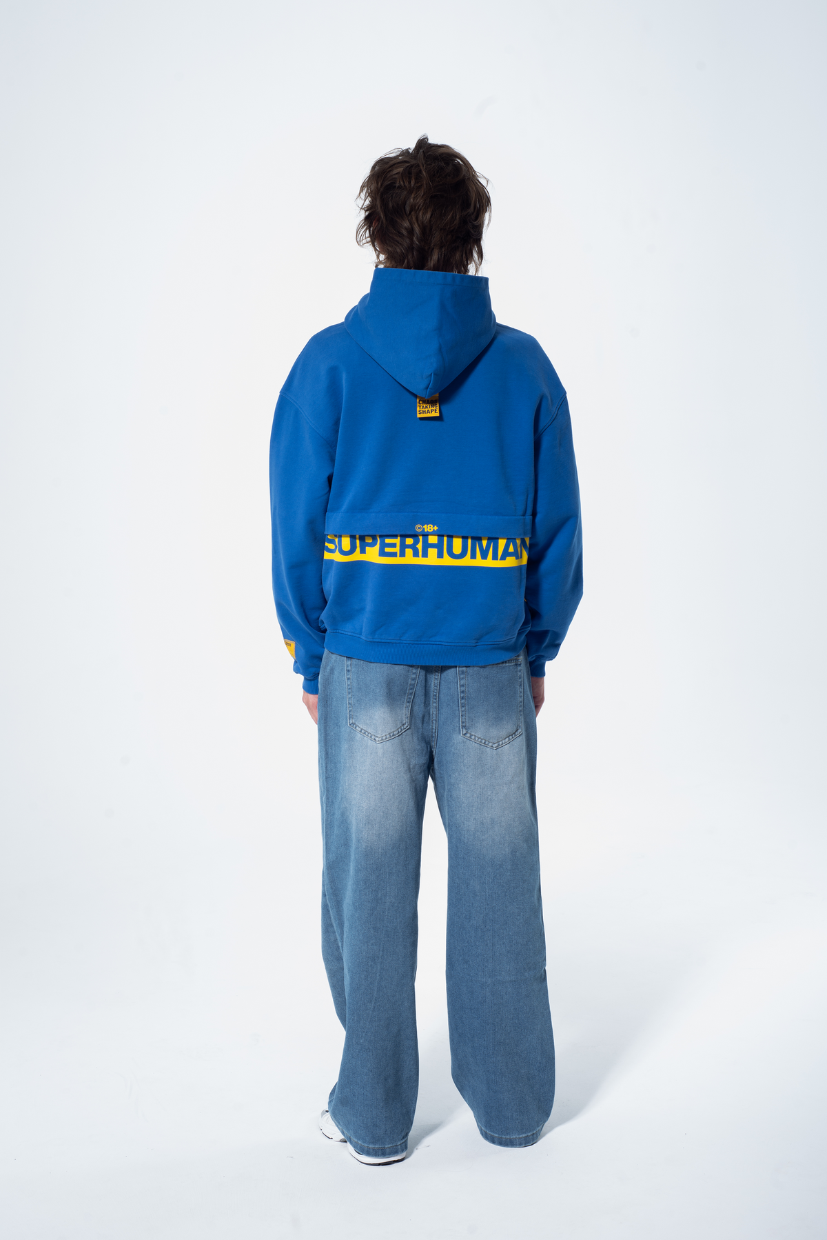 Model in the Haresquare Superhuman Nautical blue hoodie with yellow print, styled with Haresquare denim jeans – unisex luxury streetwear from Ireland.