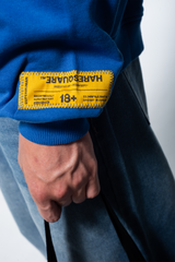 Model in the Haresquare Superhuman Nautical blue hoodie with yellow print, styled with Haresquare denim jeans – unisex luxury streetwear from Ireland.