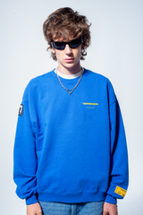 Model in the Haresquare Superhuman Nautical Blue sweatshirt with Yellow print, styled with Haresquare Blue denim jeans and haresquare bag – unisex luxury streetwear from Ireland.