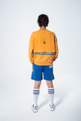 Model in the Haresquare Superhuman Apricot Tan sweatshirt with Blue print, styled with Haresquare Blue shorts – unisex luxury streetwear from Ireland.