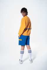 Model in the Haresquare Superhuman Apricot Tan sweatshirt with Blue print, styled with Haresquare Blue shorts – unisex luxury streetwear from Ireland.