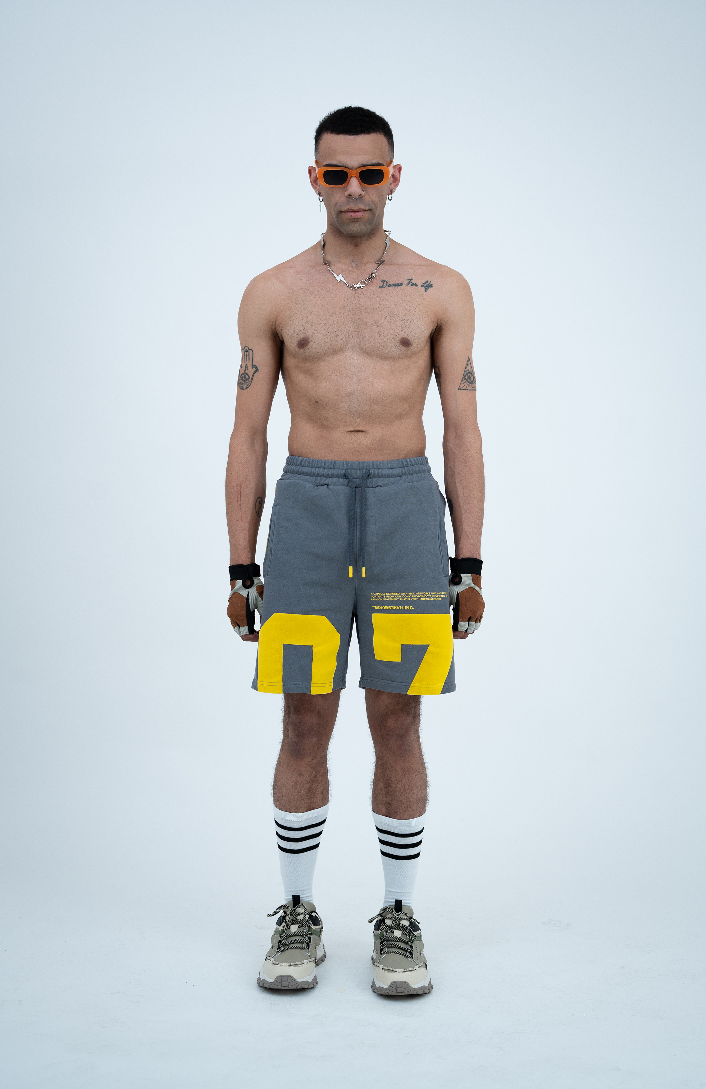 Model in the Haresquare steel grey shorts with a yellow print, styled with Haresquare luxury sunglasses – unisex luxury streetwear from Ireland.