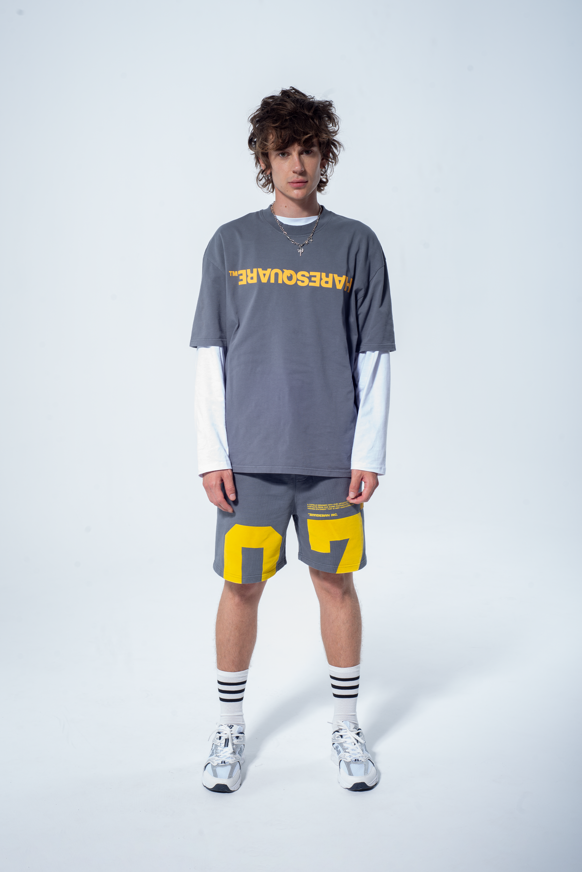 Model in the Haresquare steel grey tshirt with a yellow print, styled with Haresquare shorts in grey – unisex luxury streetwear from Ireland.