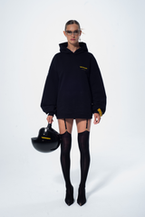 Model in the Haresquare Superhuman black hoodie with yellow print, styled with black helmet – unisex luxury streetwear from Ireland.