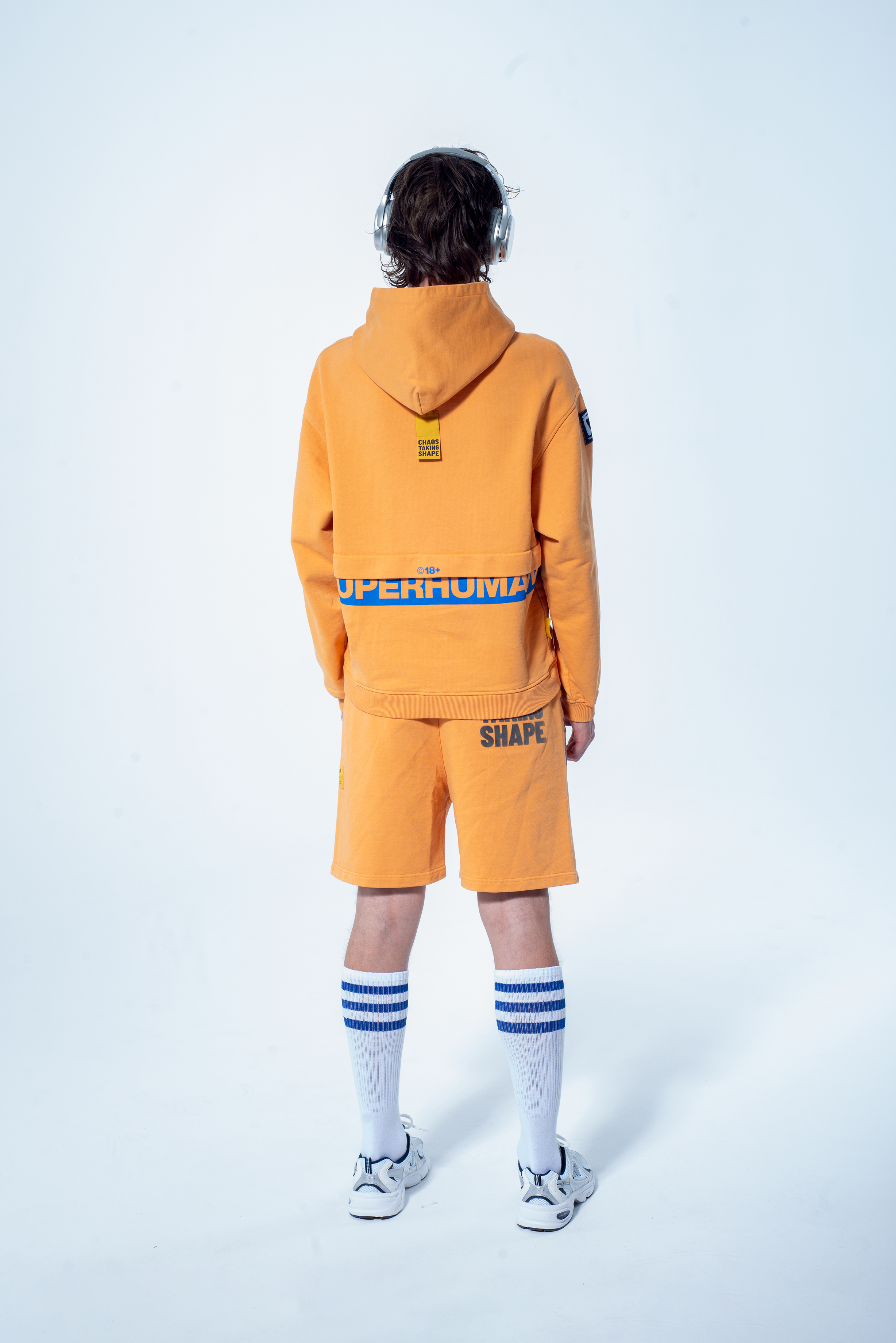 Model in the Haresquare Superhuman Apricot tan hoodie with Blue print, styled with Haresquare shorts – unisex luxury streetwear from Ireland.