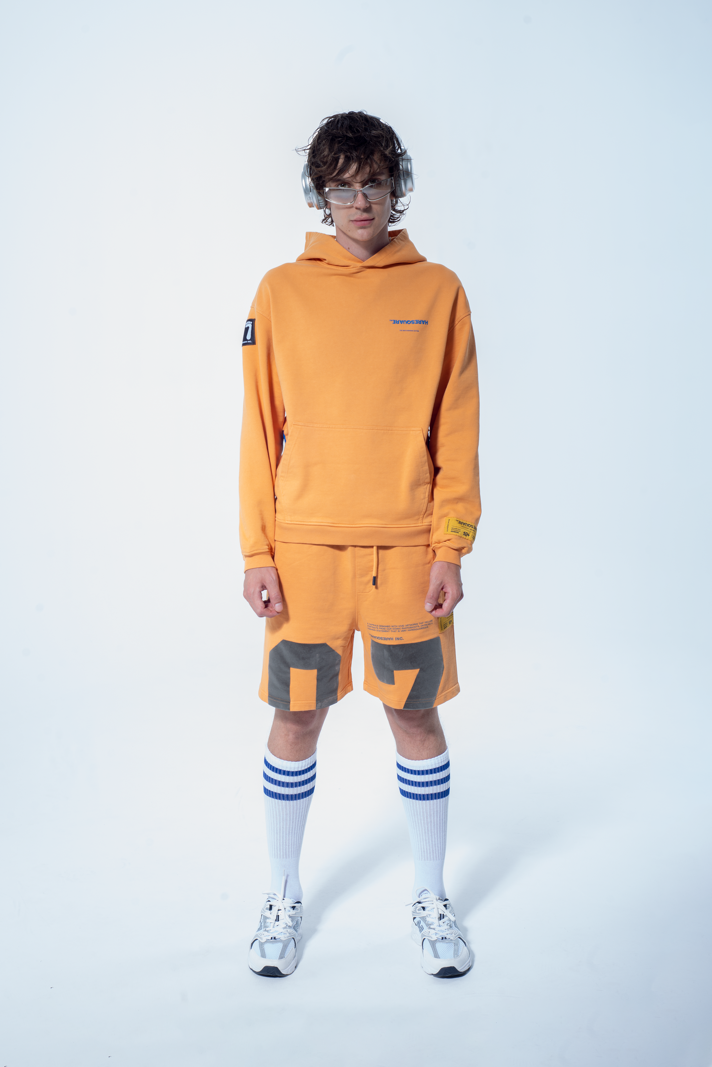 Model in the Haresquare Superhuman Apricot tan hoodie with Blue print, styled with Haresquare shorts – unisex luxury streetwear from Ireland.