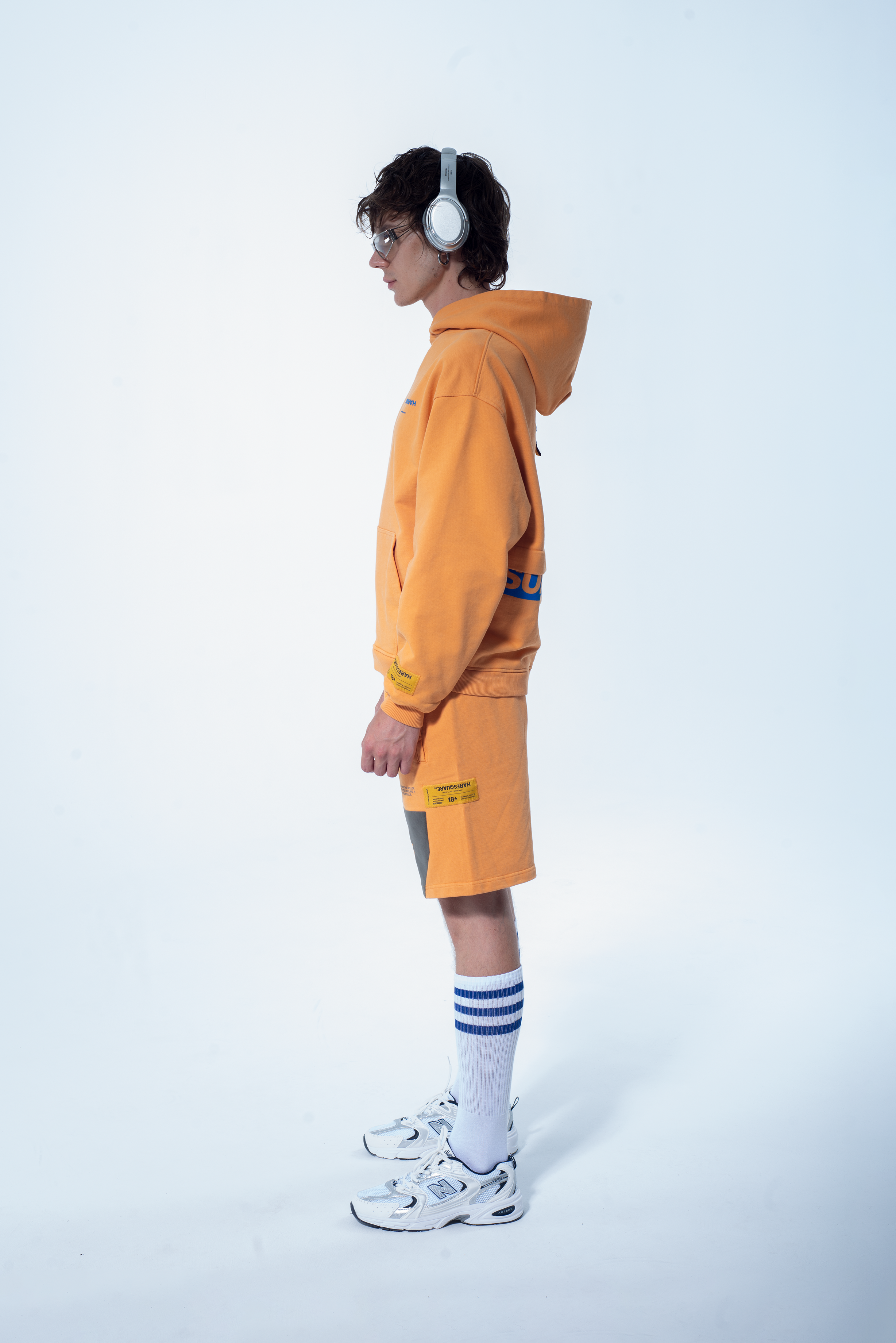 Model in the Haresquare Superhuman Apricot tan hoodie with Blue print, styled with Haresquare shorts – unisex luxury streetwear from Ireland.