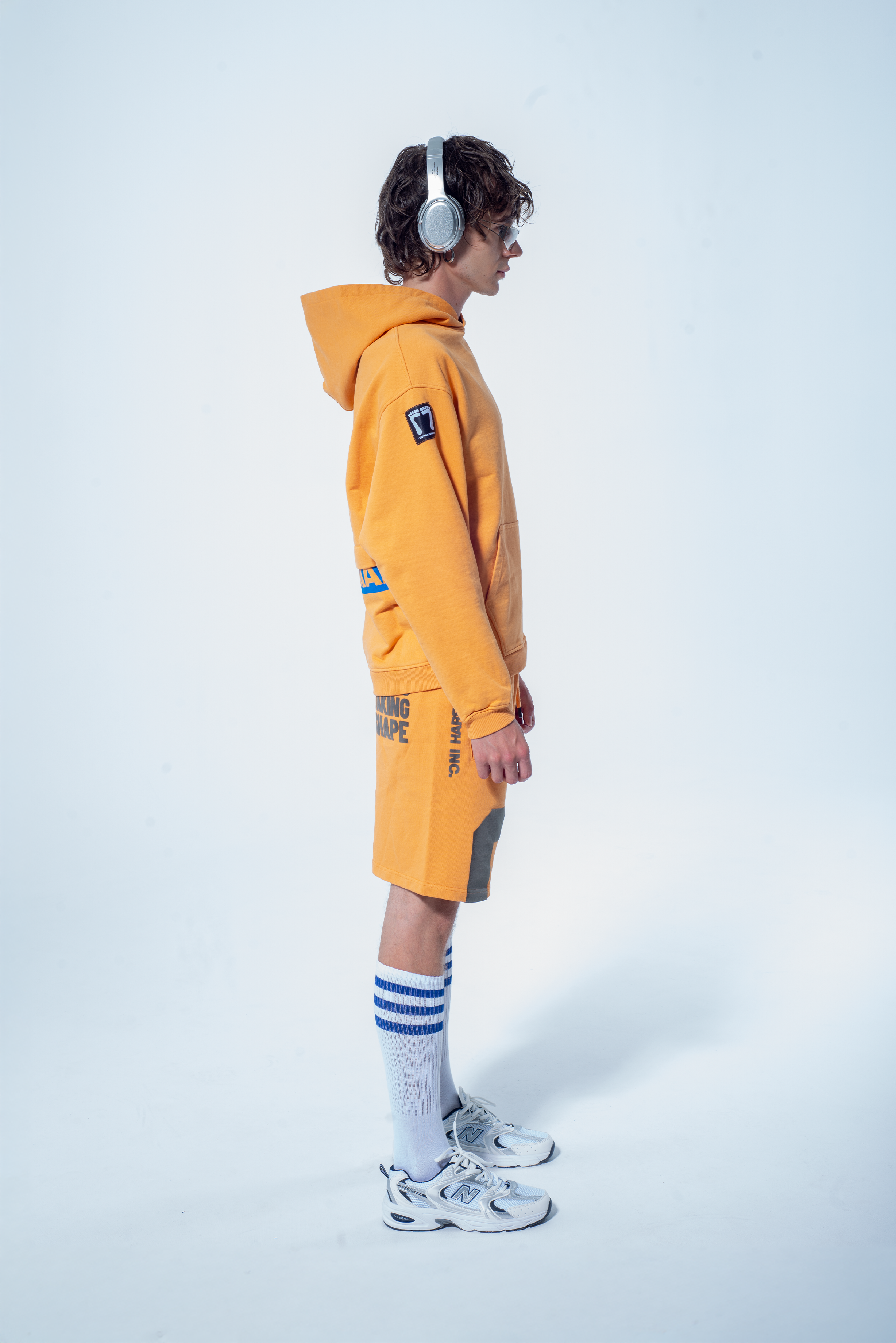 Model in the Haresquare Superhuman Apricot tan hoodie with Blue print, styled with Haresquare shorts – unisex luxury streetwear from Ireland.